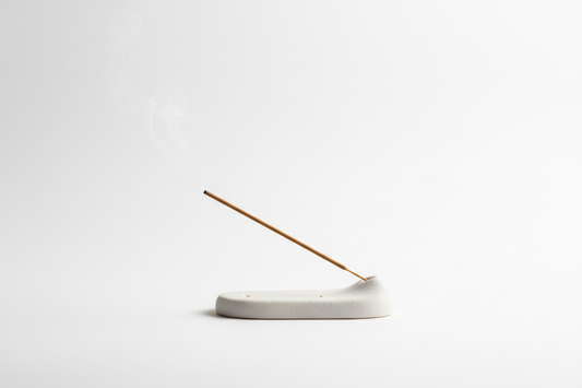 A lit coreless incense stick resting on a ceramic holder, soft smoke rising, zen home aesthetic by STILL ATARAXIA
